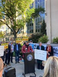 Man at podium, speaking at an outside rally, campaigning against gas pipelines.